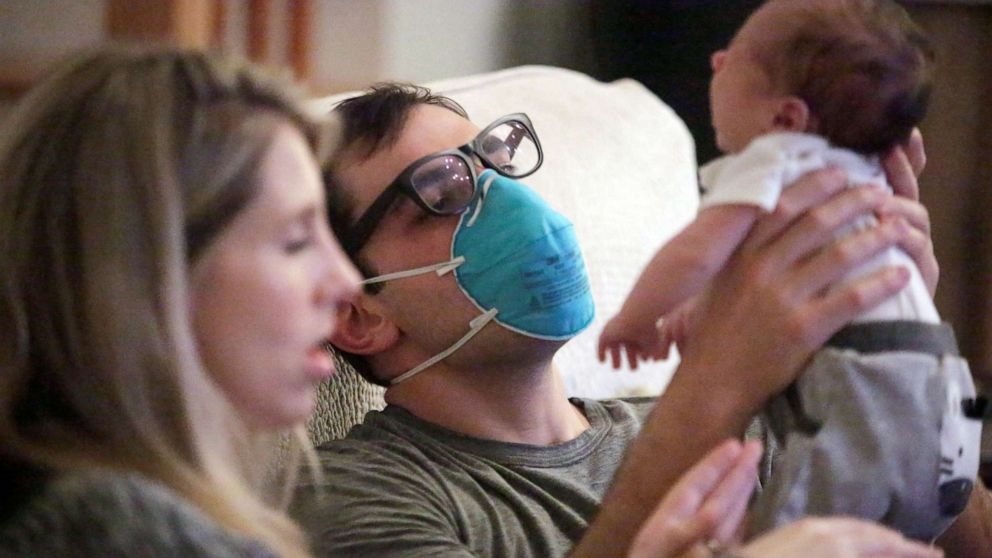 PHOTO: Emergency medicine physician Thomas Krajewski wears a mask as he holds his baby Cal with his wife Genevieve after finishing his shift amid an outbreak of coronavirus disease in New Orleans, March 27, 2020