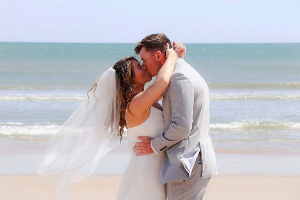 PHOTO: Savannah Kulenic and Dylan Perkins kiss during their wedding ceremony on a North Carolina beach, April 10, 2020.