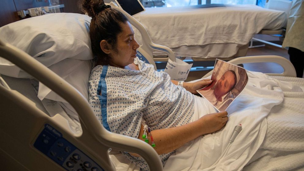 PHOTO: COVID-19 patient Zully looks at a photo of her newborn baby Neysel while in a Stamford Hospital ICU on April 24, 2020, in Stamford, Conn.