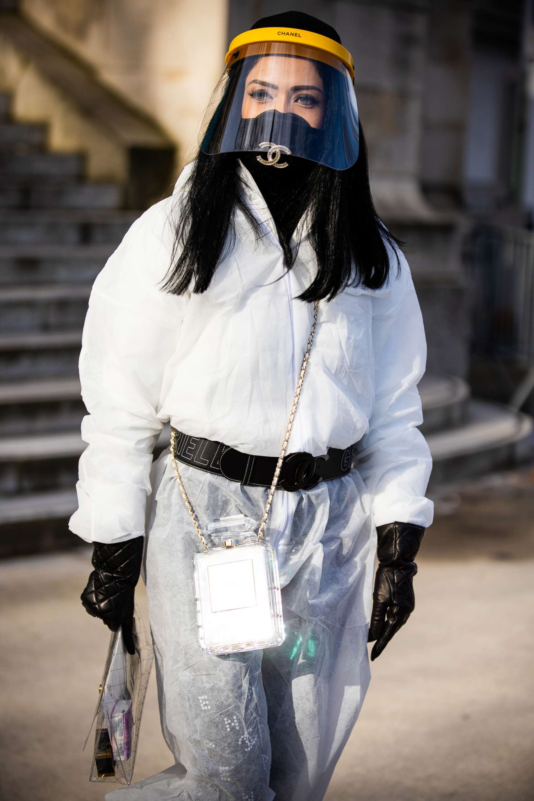 PHOTO: A guest, wearing white nonwoven coverall, Chanel mask, belt and bag full of hand sanitizer, is seen outside the Chanel show during Paris Fashion Week Womenswear Fall/Winter 2020/2021, March 3, 2020 in Paris.