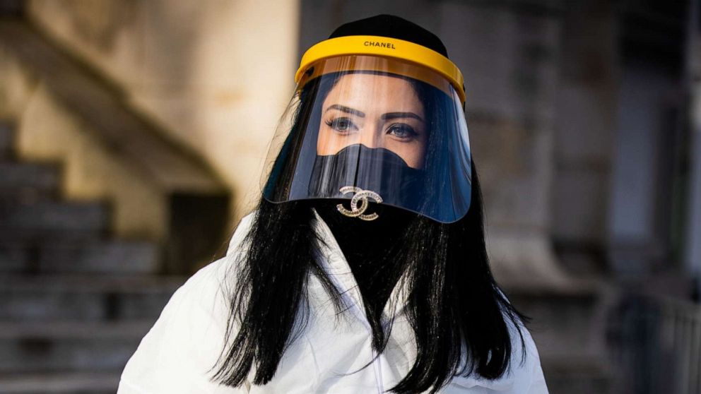 PHOTO: A guest, wearing white nonwoven coverall, Chanel mask, belt and bag full of hand sanitizer, is seen outside the Chanel show during Paris Fashion Week Womenswear Fall/Winter 2020/2021, March 3, 2020 in Paris.