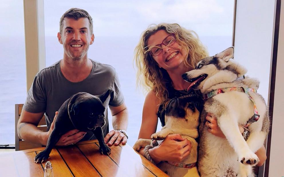 PHOTO: Dustin Leonard and Helena Franczak pose with the three dogs they were traveling with on their catamaran in the South Pacific.