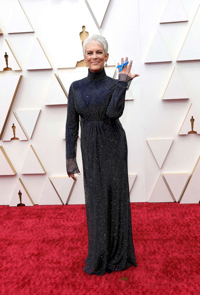 PHOTO: Jamie Lee Curtis wearing Stella McCartney holds a ribbon supporting refugees as she poses on the red carpet during the Oscars arrivals at the 94th Academy Awards in Hollywood, Calif., March 27, 2022. 