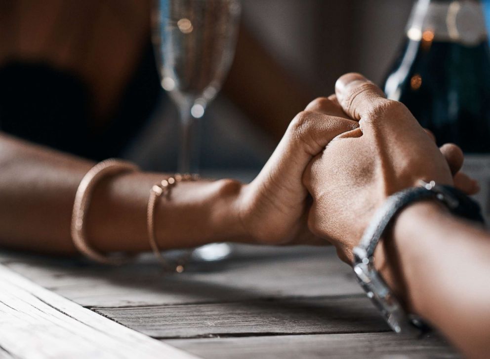 PHOTO: A stock photo of a couple holding hands at a table.