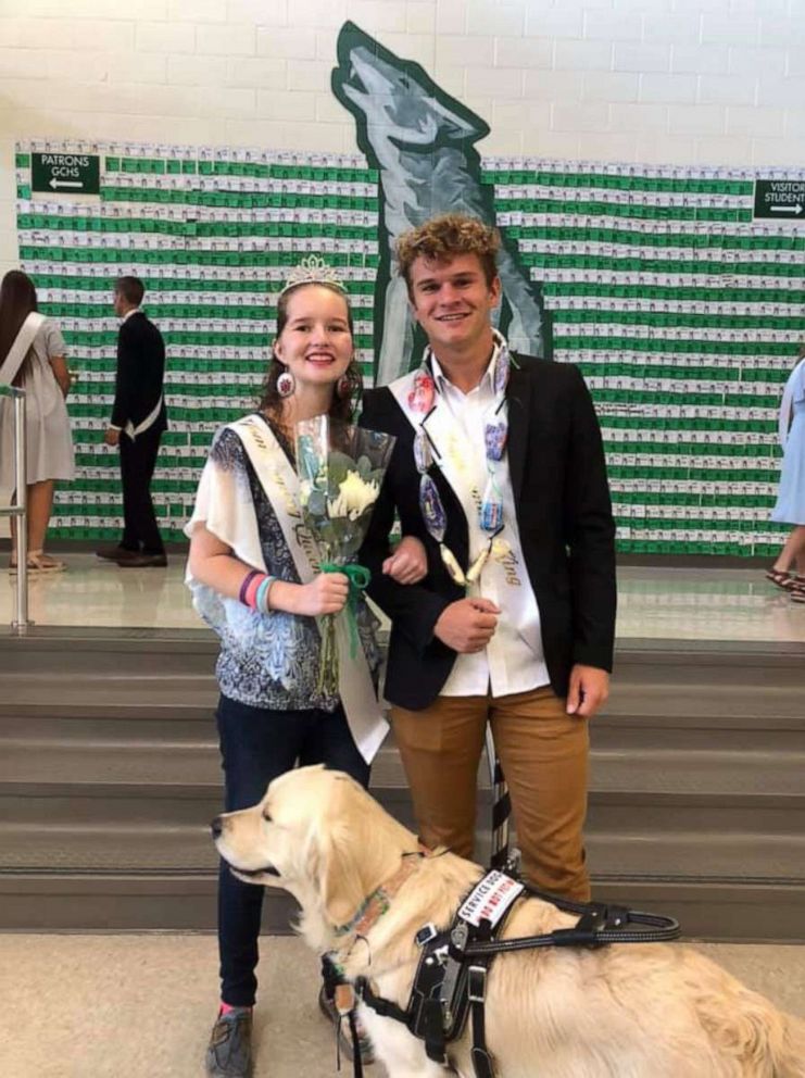 PHOTO: Deserae Turner and the homecoming king pose with her service dog at their school's homecoming assembly.