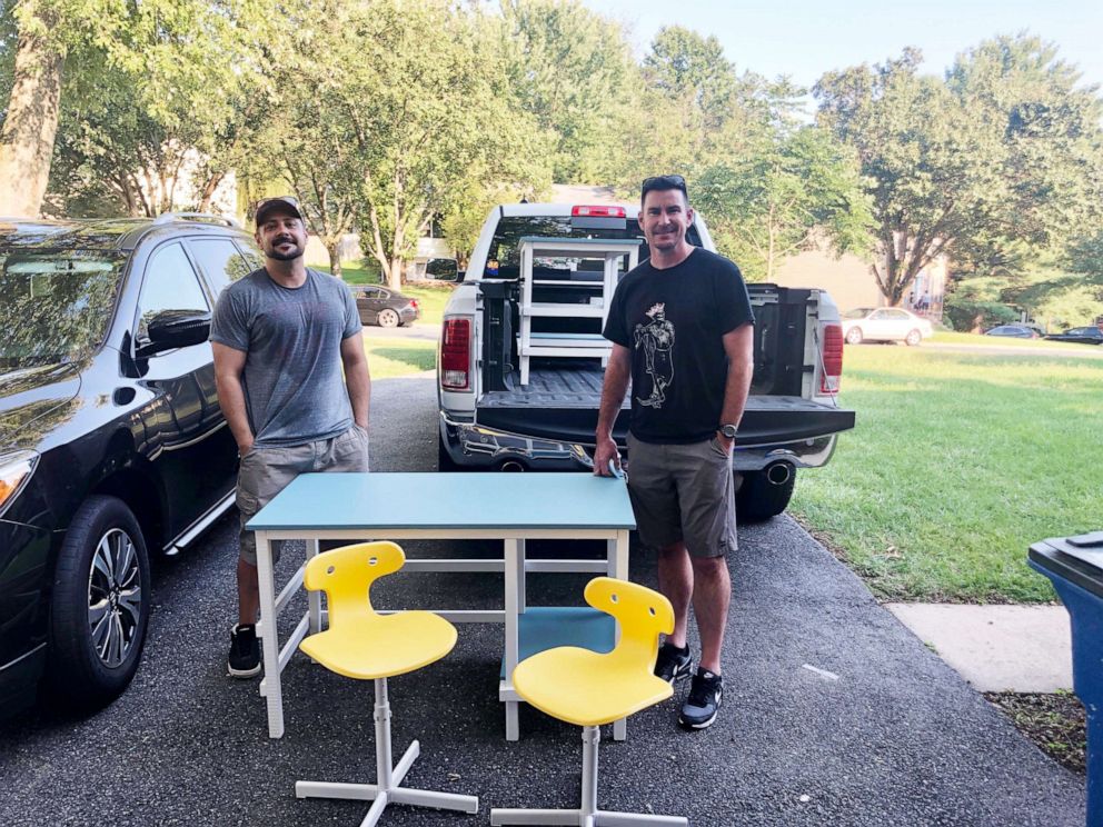 PHOTO:  Members of Desks by Dads stand with one of the more than 30 desks the group has made and distributed for students studying at home during the coronavirus pandemic.
