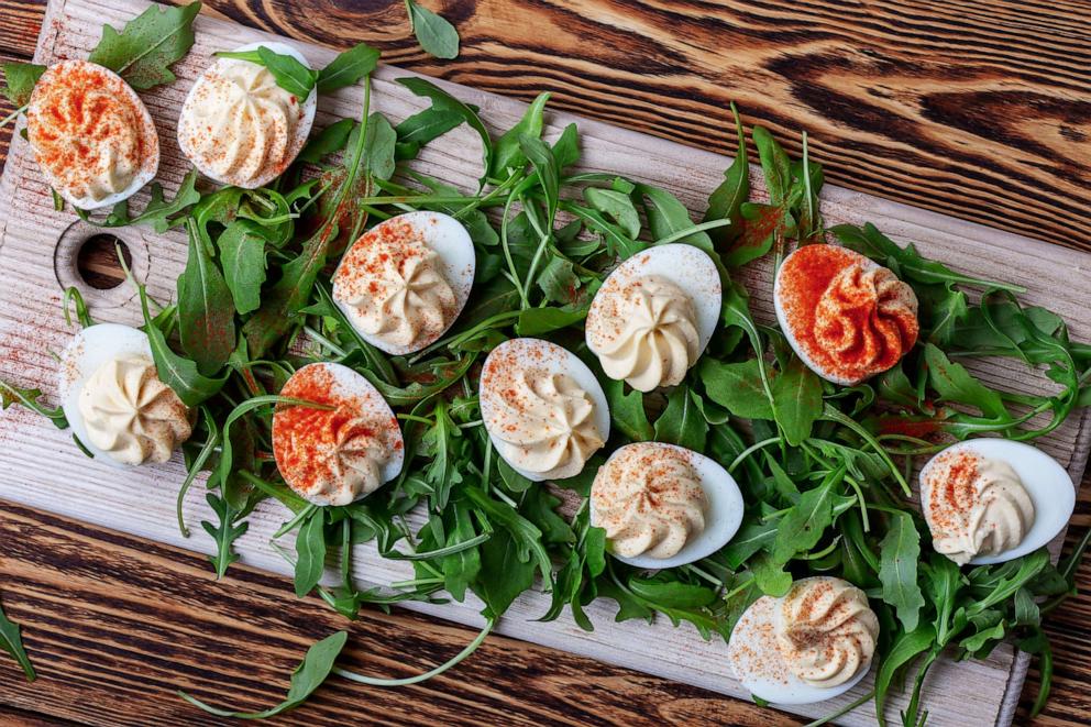 PHOTO: Deviled eggs with paprika on fresh arugula salad on wooden table.