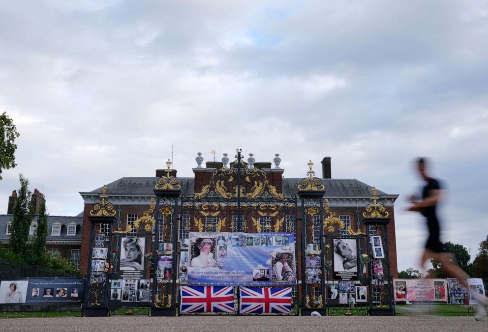 PHOTO: A man runs by portraits of Princess Diana displayed on the gates of Kensington Palace, in London, Aug. 30, 2022. 