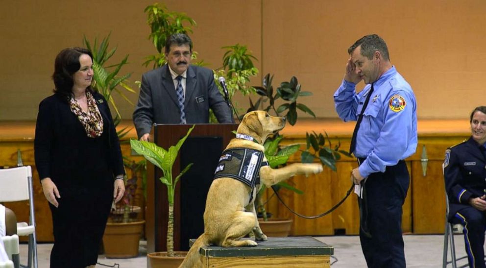 PHOTO: A first responder salutes his new dog at the Puppies Behind Bars graduation ceremony. 
