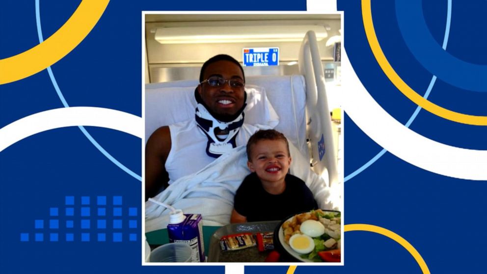 PHOTO: Dr. Feranmi Okanlami with his son Alex in a hospital bed after a spinal cord injury.