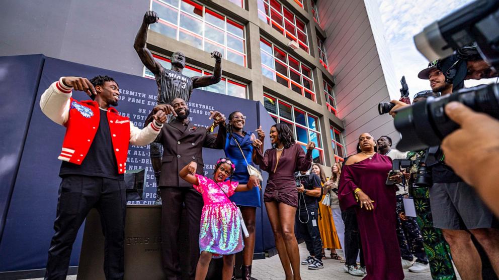 PHOTO: Dwyane Wade and his family strike the pose depicted in the statue after it was unveiled in front of Kaseya Center, Oct. 27, 2024, in Miami. 