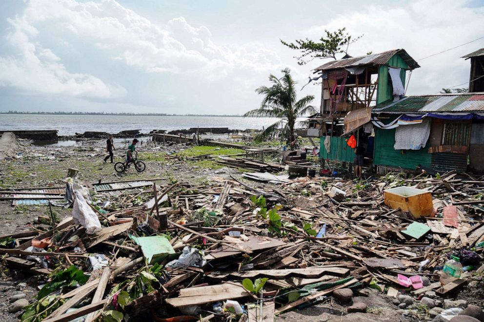 PHOTO: Residents walk past a house damaged during Typhoon Phanfone in Tacloban, Leyte province in the central Philippines, Dec. 25, 2019. 