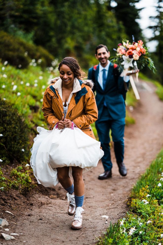 PHOTO: A bride holds her wedding dress while the groom holds the flowers during an adventure elopement.