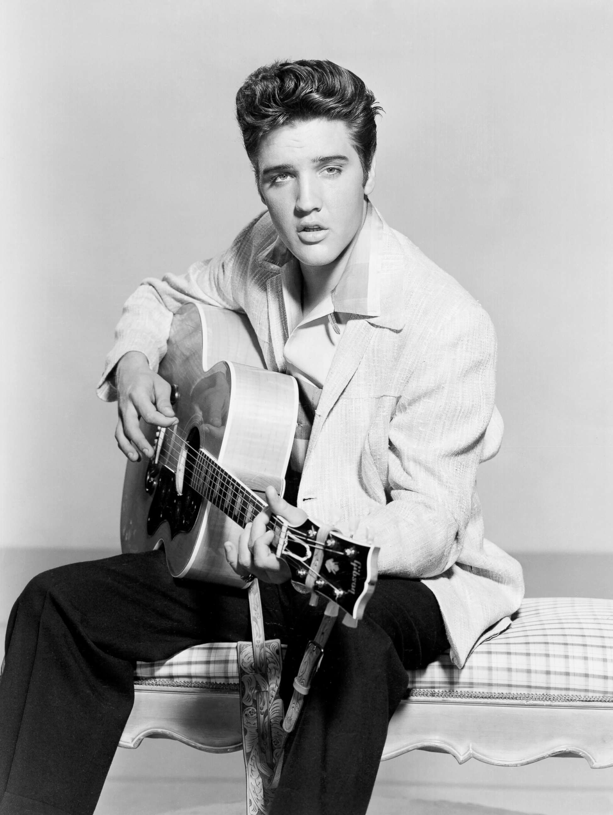 PHOTO: Elvis Presley strums his acoustic guitar in a portrait in 1956. 