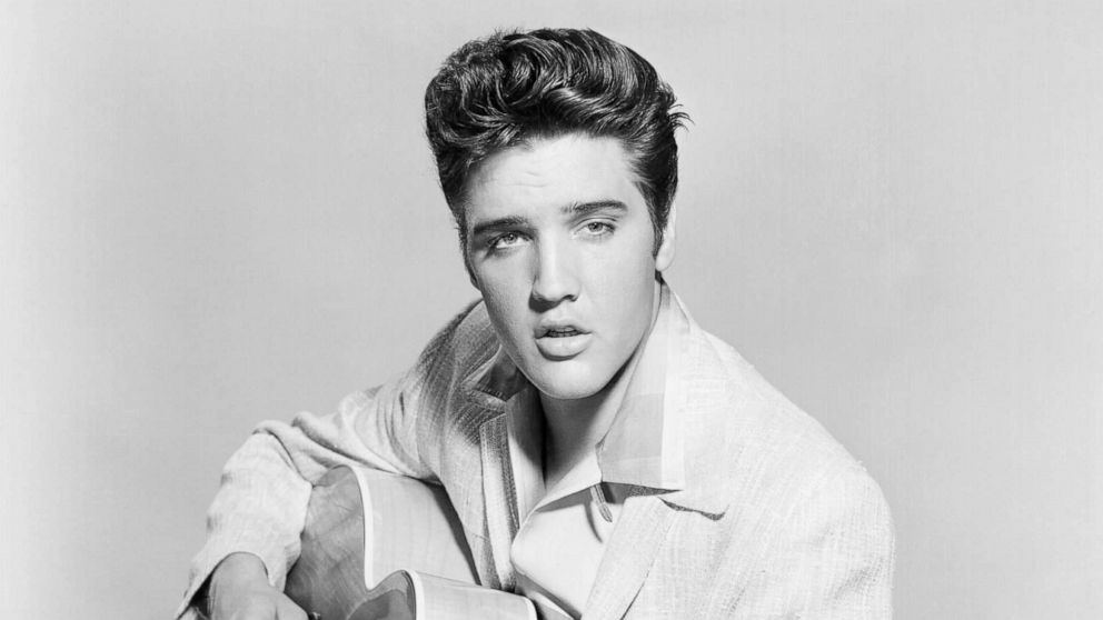 PHOTO: Elvis Presley strums his acoustic guitar in a portrait in 1956. 