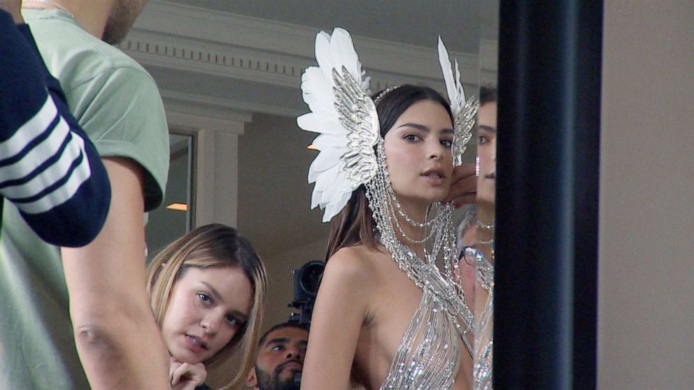 PHOTO: Model Emily Ratajkowski gets ready for the 2019 Met Gala in a custom Peter Dundas nude and silver embroidered cut out gown with long train and crystal and feather headpiece by House of Malakai.