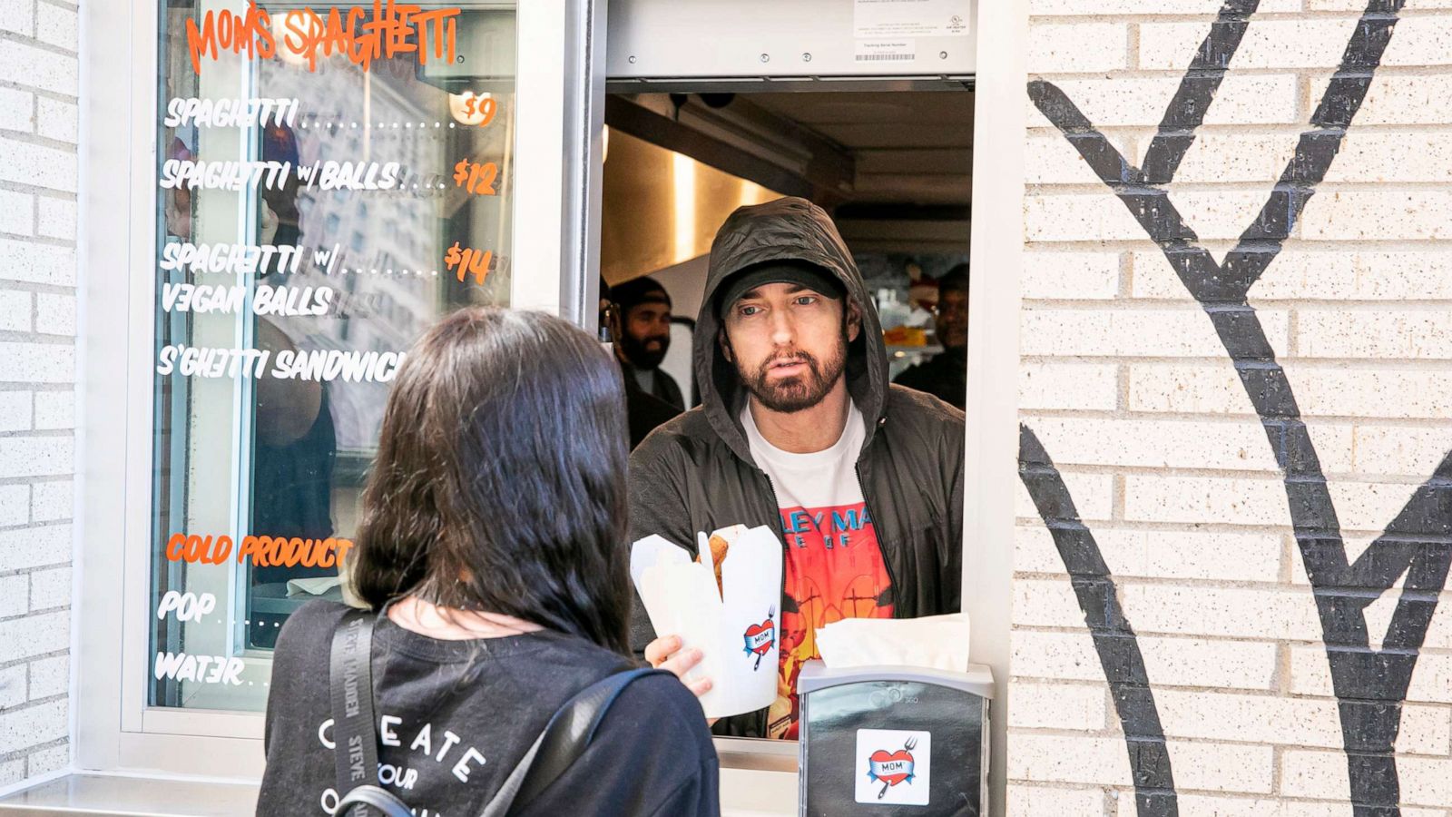 PHOTO: Eminem serves Mom's Spaghetti to a fan on the opening night of his restaurant "Mom's Spaghetti" in Detroit, Sept. 29, 2021.