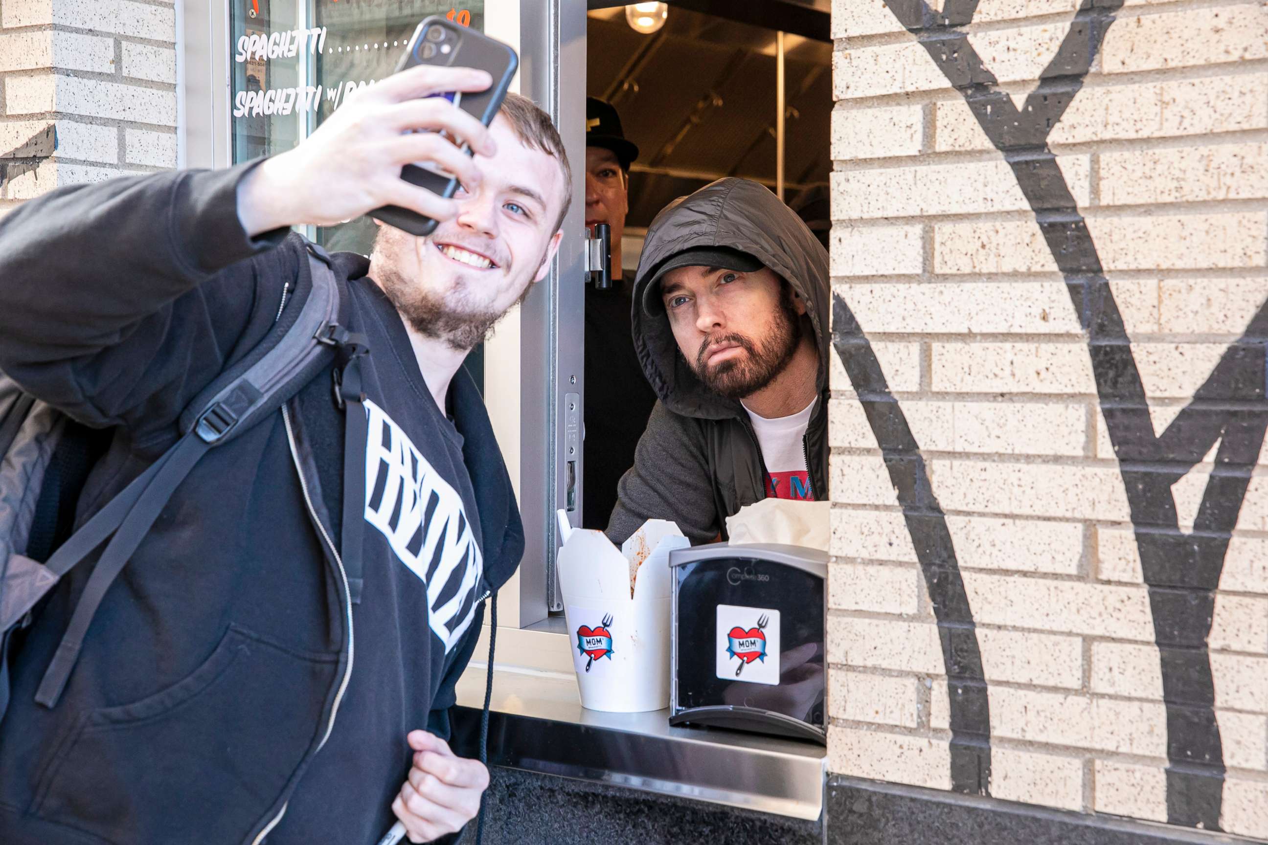 PHOTO: Eminem serves Mom's Spaghetti and takes a selfie with a fan on the opening night of his restaurant "Mom's Spaghetti" in Detroit, Sept. 29, 2021.