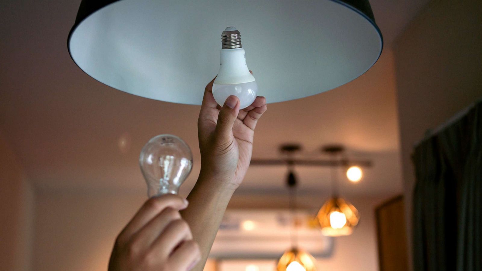 PHOTO: Replacing an incandescent light bulb with an energy efficient LED bulb.