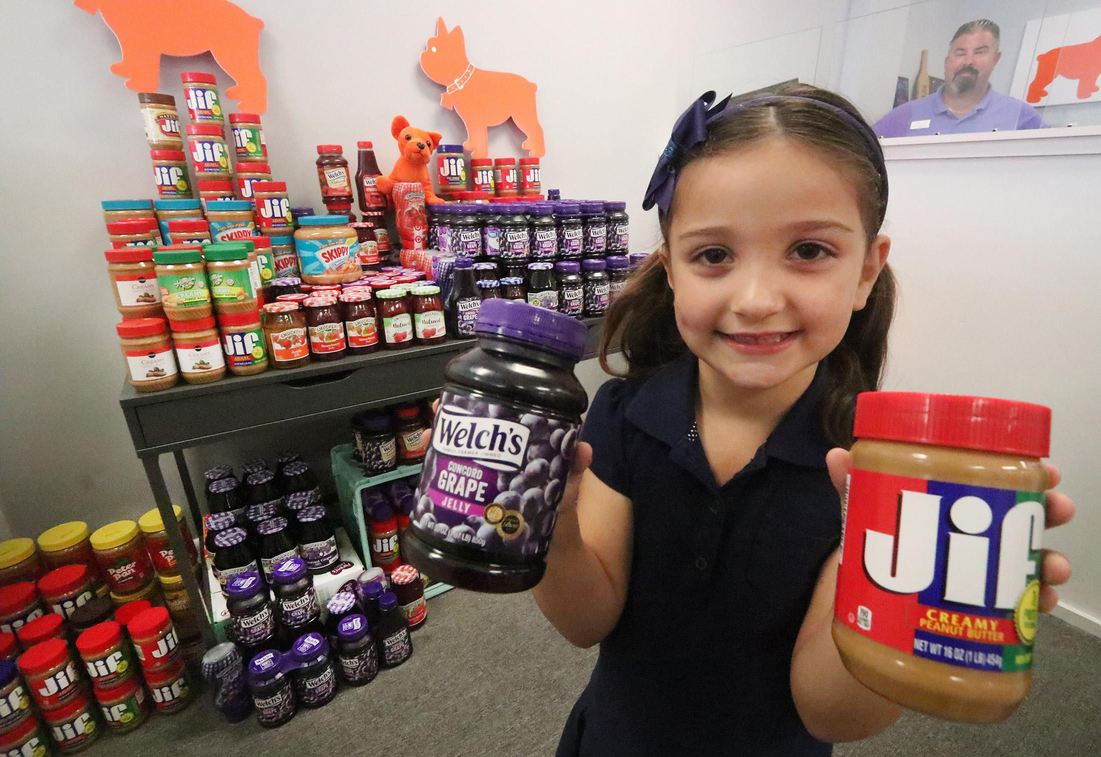 PHOTO: Eva Chapman, a six year old Spruce Creek Elementary kindergartener, holds a couple of the hundred or more jars of peanut butter and jelly she collected for a food drive, May 13, 2019 so kids won’t go hungry over the summer. 