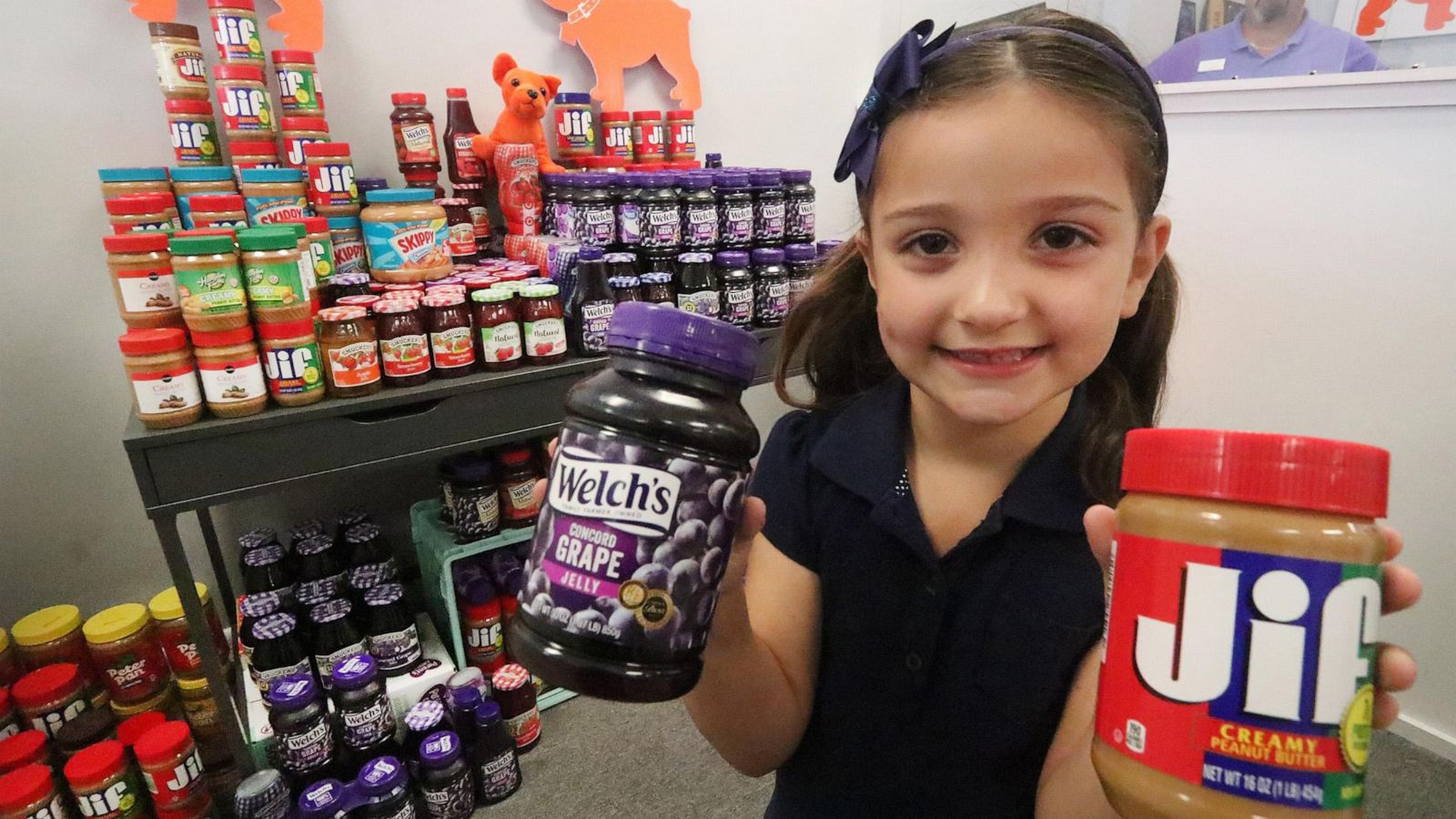 PHOTO: Eva Chapman, a six year old Spruce Creek Elementary kindergartener, holds a couple of the hundred or more jars of peanut butter and jelly she collected for a food drive, May 13, 2019 so kids won’t go hungry over the summer.