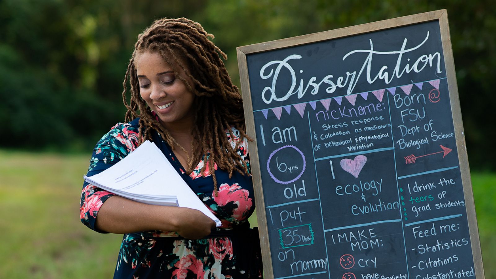 PHOTO: Eve Humphrey poses with her dissertation in a newborn photoshoot spoof after she completed her doctorate in biology at Florida State University in fall 2019.