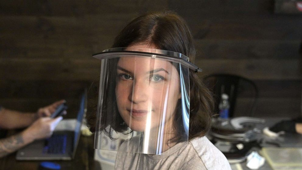 PHOTO: Argentinian graphic designer Veronica Acevedo and her husband Mariano San Sebastian, left, make plastic face shields for sale at their home in Buenos Aires, April 17, 2020.