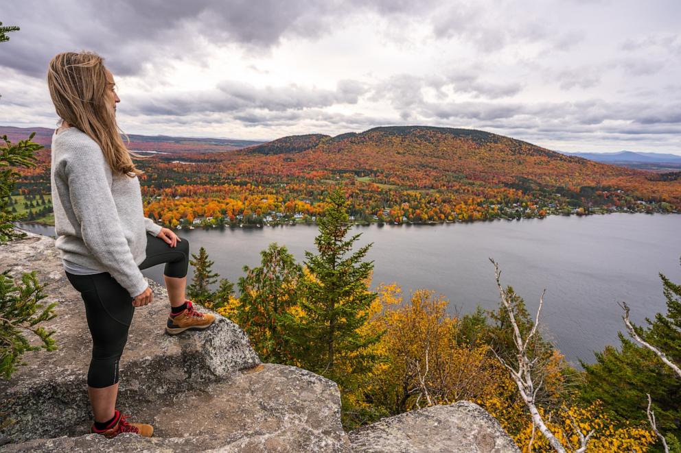 PHOTO: Woman looking at Lyster lake with forest of Quebec and Vermont seen from the Mount Pinacle in Coaticook during autumn.