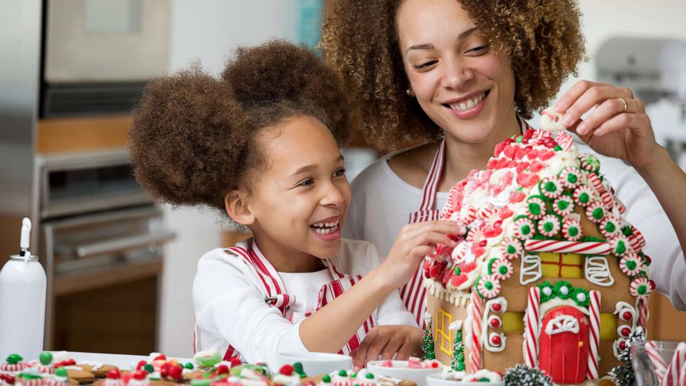 PHOTO: In this stock photo, mother and daughter decorate a gingerbread house during the Christmas season.
