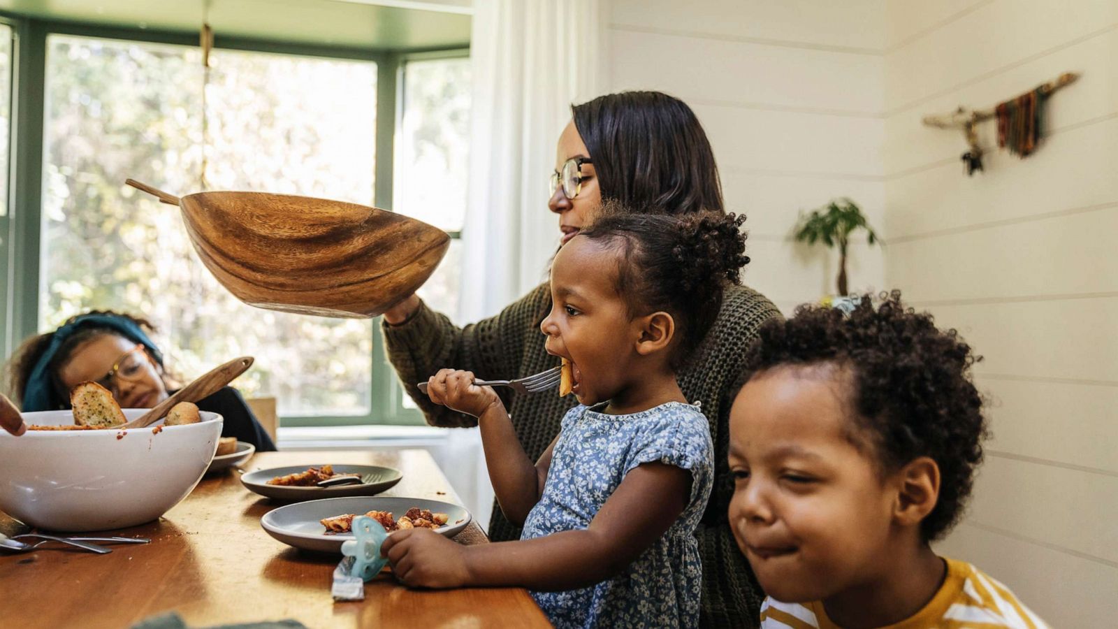 PHOTO: In this stock image, a mother feeds her children dinner at home.