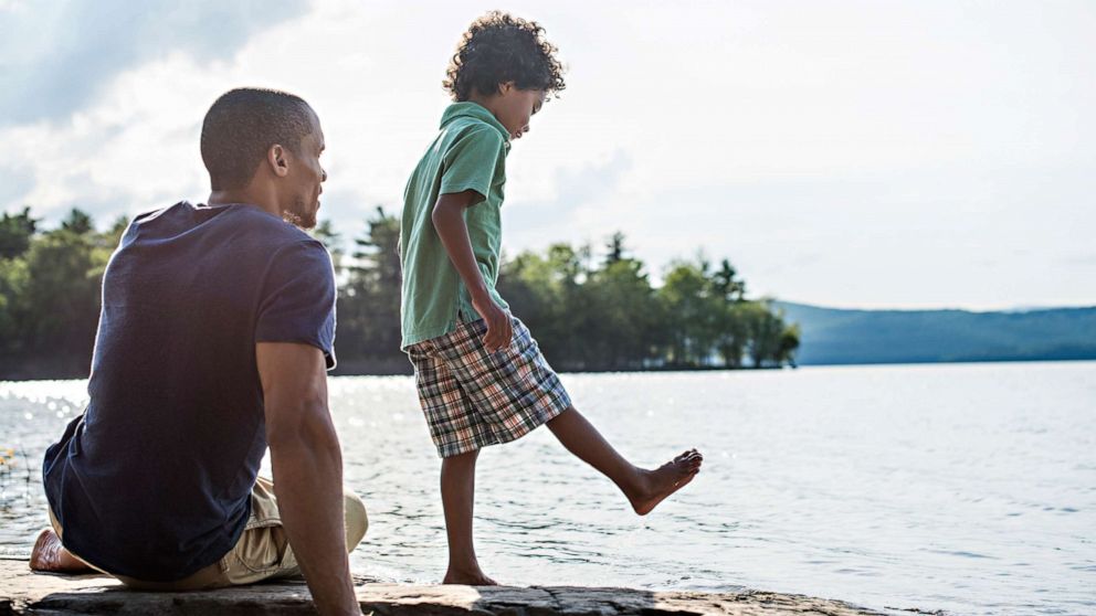 PHOTO: A father and son on a lake shore in summer.