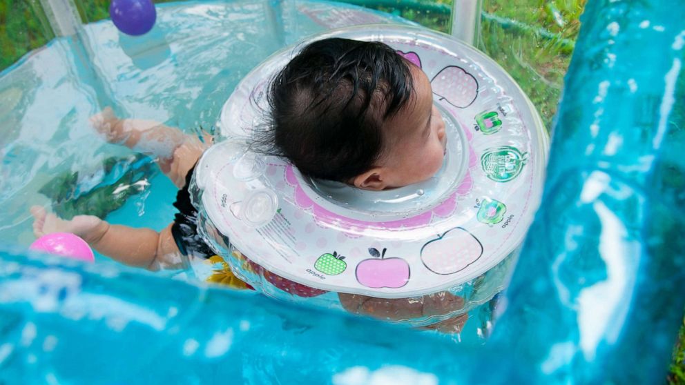 PHOTO: A baby girl swims while wearing an infant neck float in Bangkok, July 29, 2017.