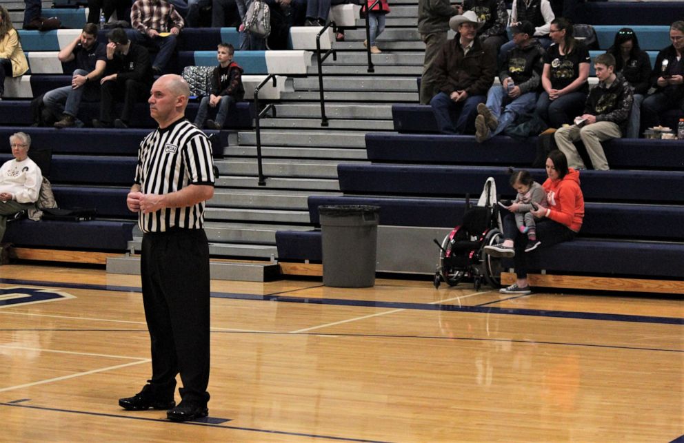 PHOTO: Finnley Foster watches her dad Pat Foster referee a high school basketball game in Great Falls, Montana, on Feb. 21, 2020. 
