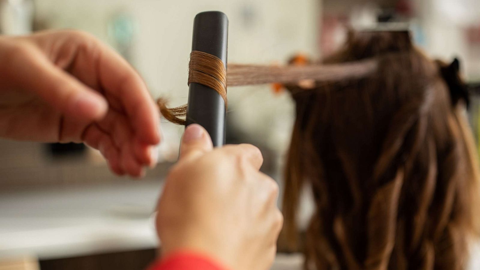 PHOTO: A hairdresser uses a flat iron at a hair salon.