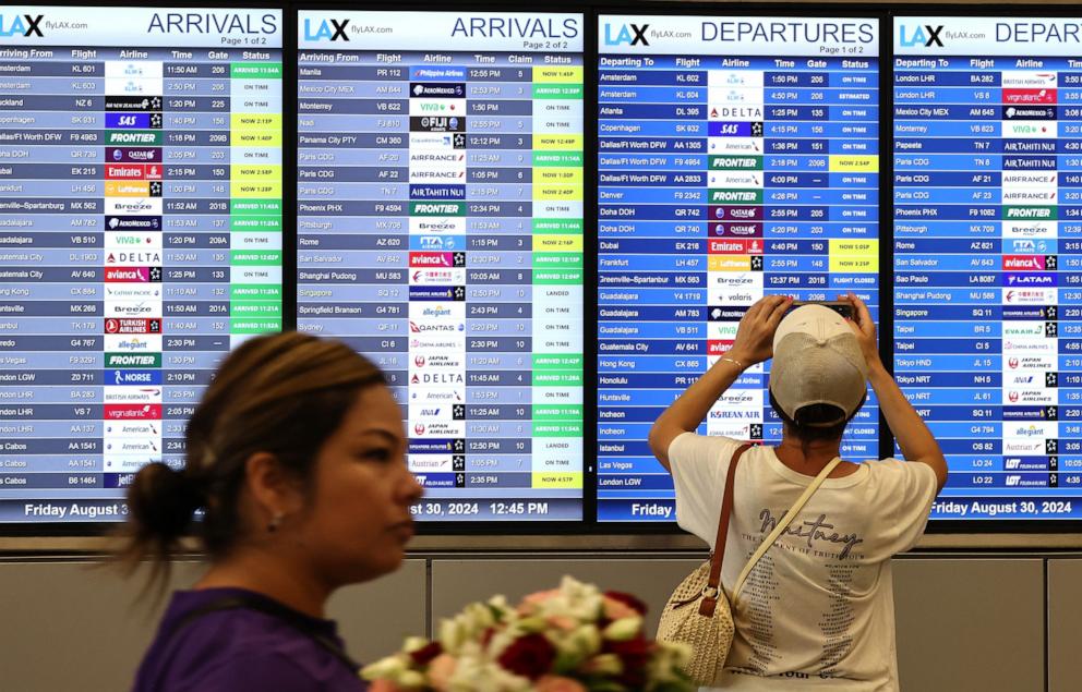 PHOTO: A person takes a photo of the departures board outside the international terminal at Los Angeles International Airport (LAX) ahead of the Labor Day holiday, Aug. 30, 2024, in Los Angeles.