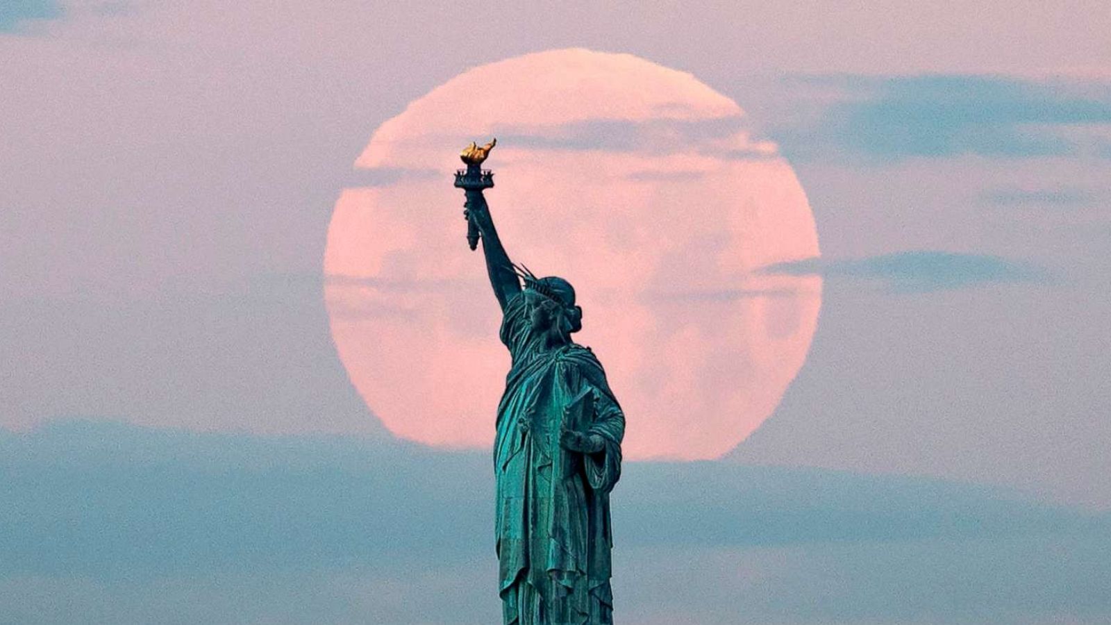 PHOTO: May's full Moon, known as the Full Flower Moon and is the last supermoon of the year, sets behind the Statue of Liberty on May 7, 2020 in New York City.