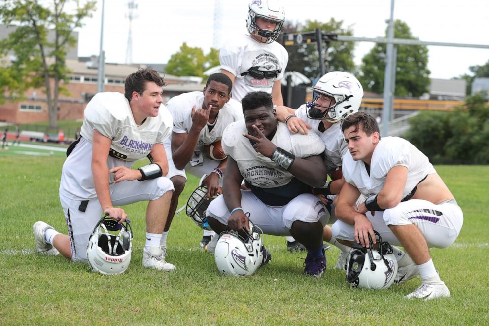PHOTO: Bloomfield Hills defensive lineman Devin Holmes, center, who is deaf, strikes a pose with teammates during practice on Wednesday, Sept. 4, 2019, at Bloomfield Hills High School.