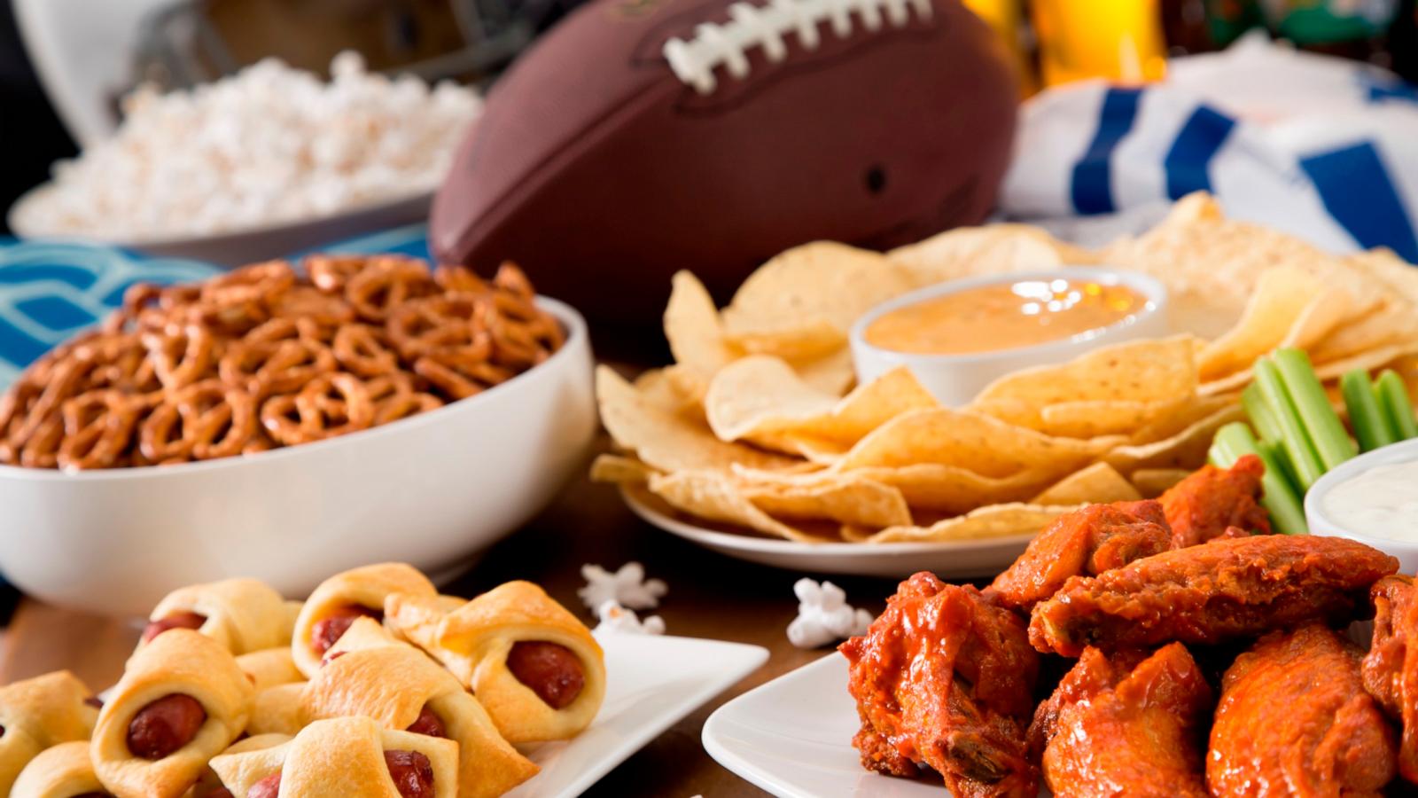 PHOTO: Hot chicken wings, nachos, beer, and popcorn, in a football party spread table.