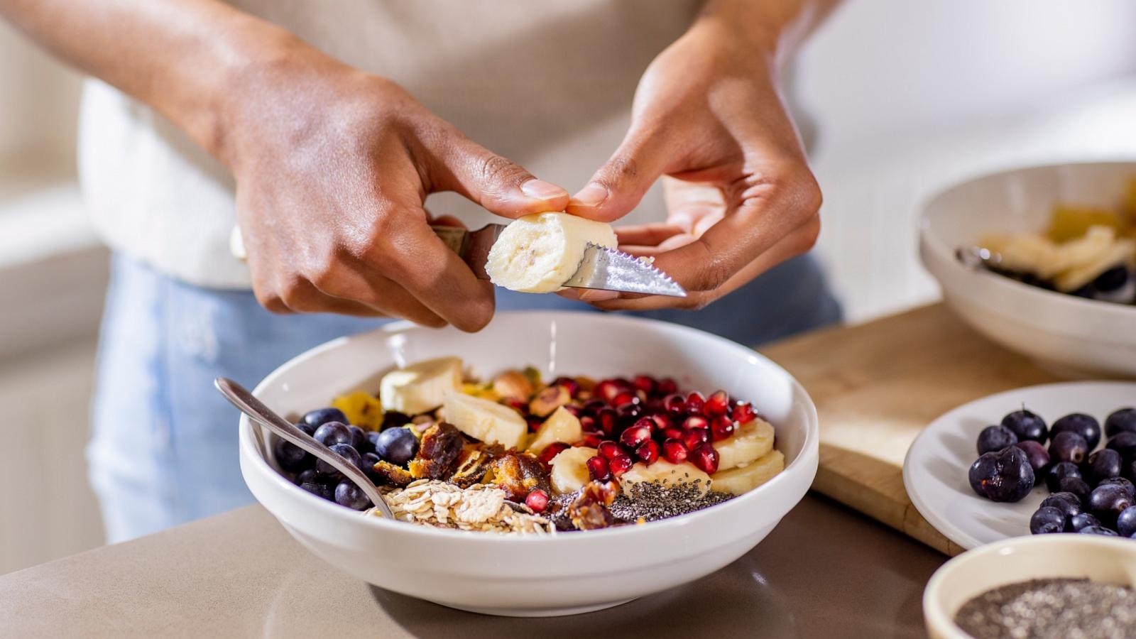 PHOTO: Stock photo of a person cutting fruit into a bowl.