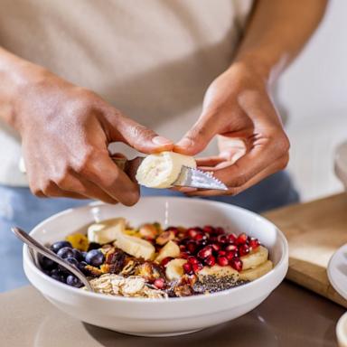PHOTO: Stock photo of a person cutting fruit into a bowl.