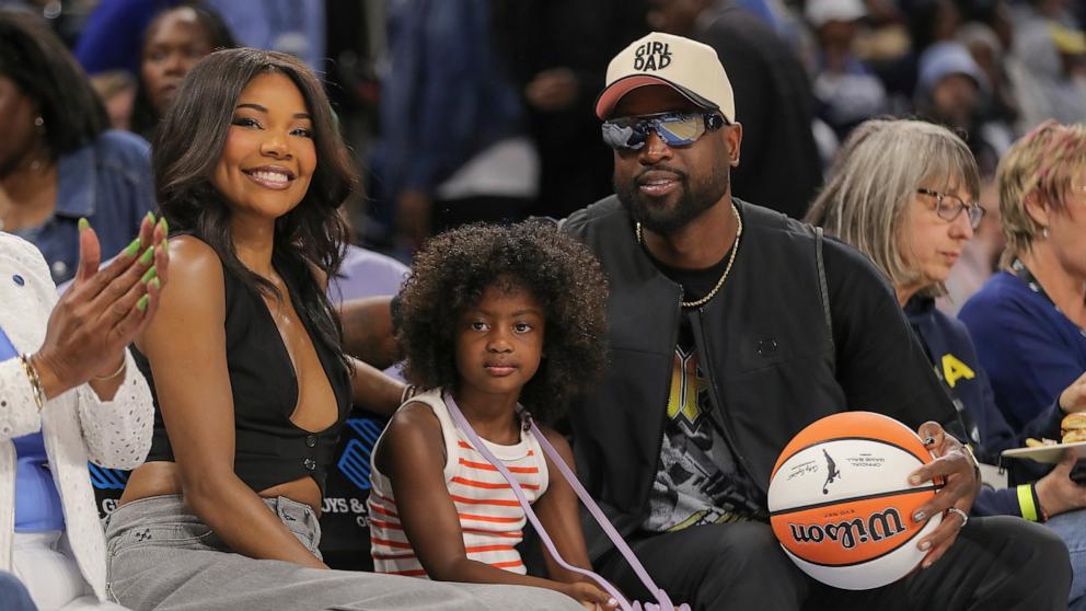 PHOTO: Gabrielle Union, left, Kaavia Wade, middle, Dwyane Wade, right, pose for a photo during he first half of a WNBA game against the Connecticut Sun and the Chicago Sky on May 25, 2024 at Wintrust Arena on in Chicago.