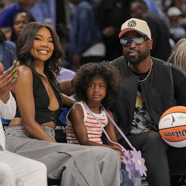 PHOTO: Gabrielle Union, left, Kaavia Wade, middle, Dwyane Wade, right, pose for a photo during he first half of a WNBA game against the Connecticut Sun and the Chicago Sky on May 25, 2024 at Wintrust Arena on in Chicago.