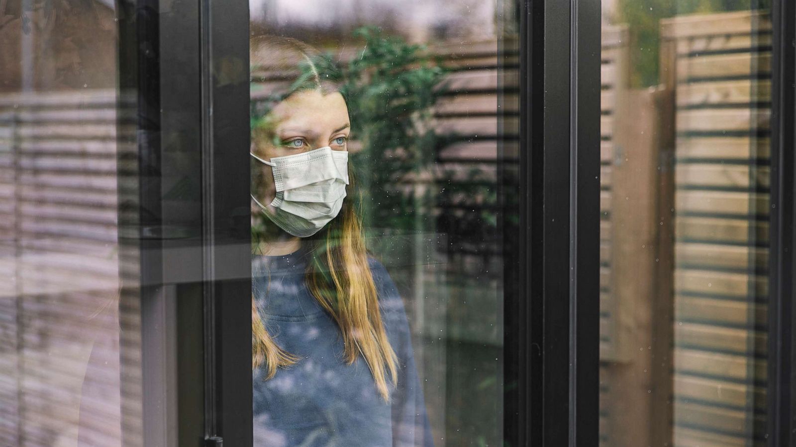 PHOTO: In this undated file photo, a girl looks out the window while wearing a mask.