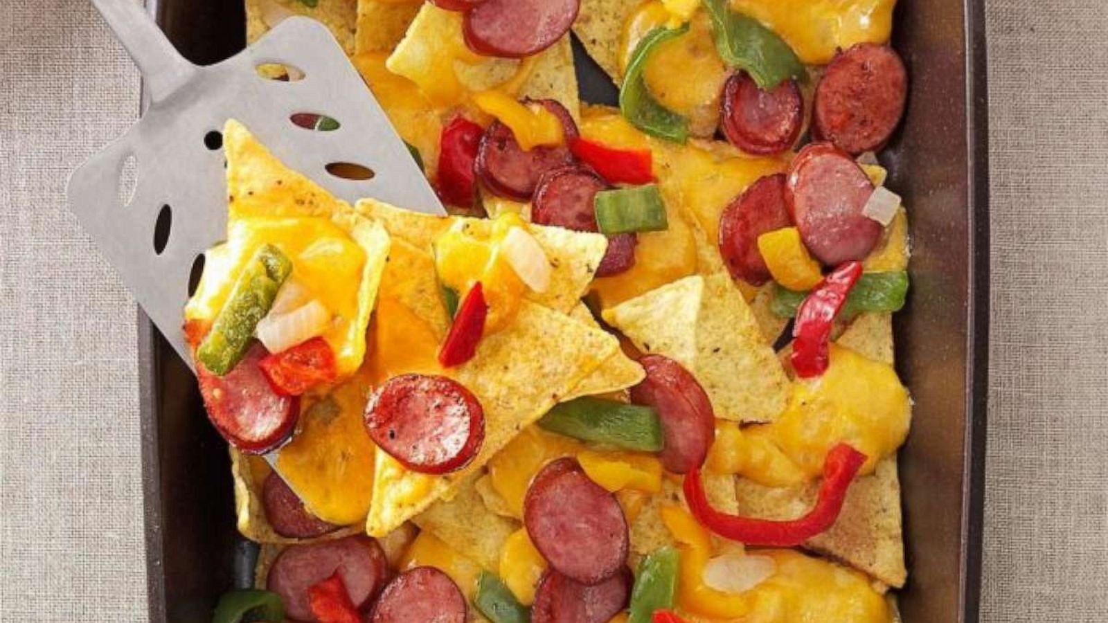 PHOTO: Nachos with sliced bratwurst links on drizzled beer-laced cheese.