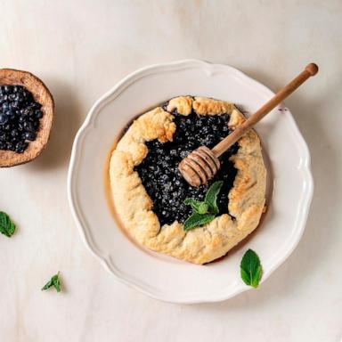 PHOTO: Home baking summer berry biscuit pie with blueberries. served in plate with bowl of blueberry and honey over white marble background. 