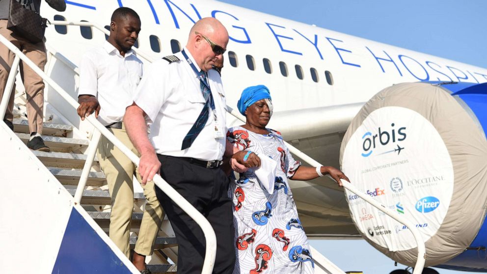 PHOTO: Peter Pitzer departs an Orbis plane in Ghana with a woman treated for a vision problem.