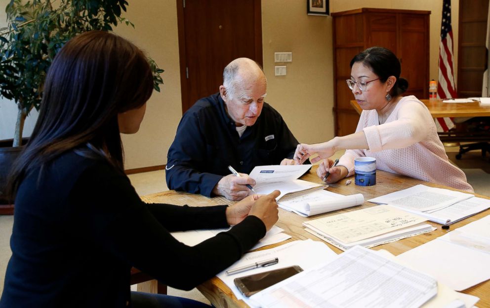 PHOTO: Gov. Jerry Brown reviews a measure with staff members Camille Wagner, left, Graciela Castillo-Krings at his Capitol office, Sept. 30, 2018, in Sacramento, Calif.