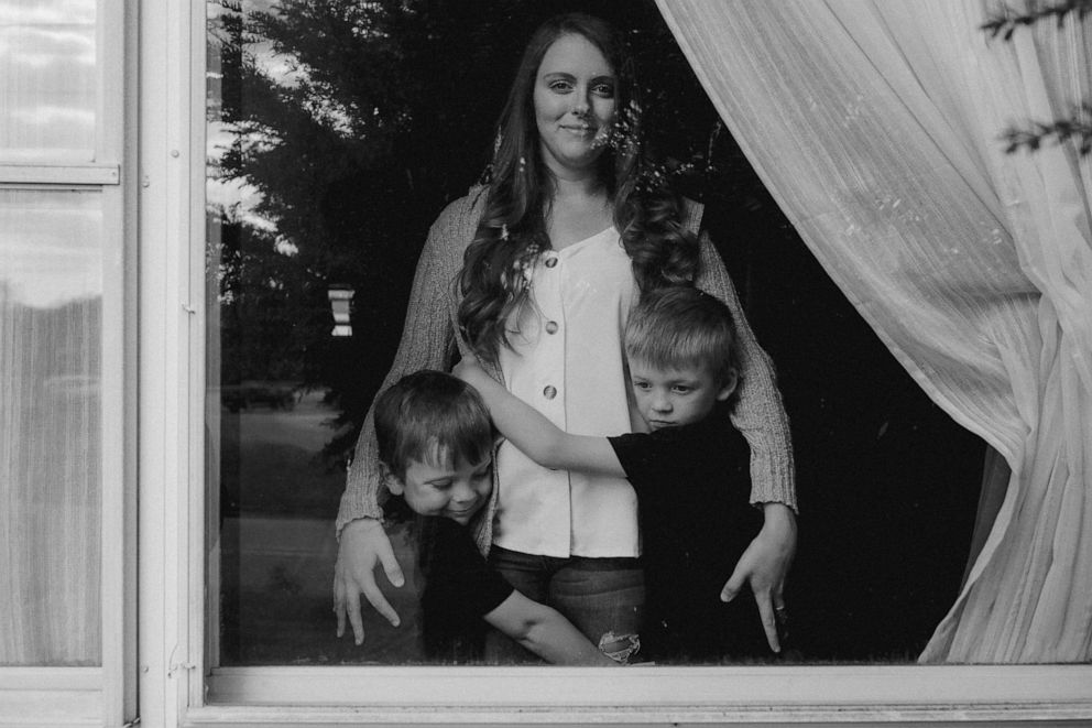 PHOTO: Two brothers hug their mother behind a window in Fairborn, Ohio.