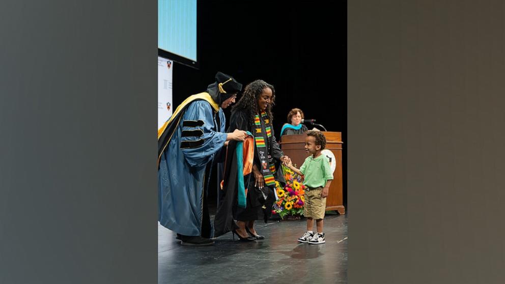 PHOTO: Princeton School of Public and International Affairs Dean Amaney Jamal helps 3-year-old Julian give his mom Natasha S. Alford her master's hood during graduation.