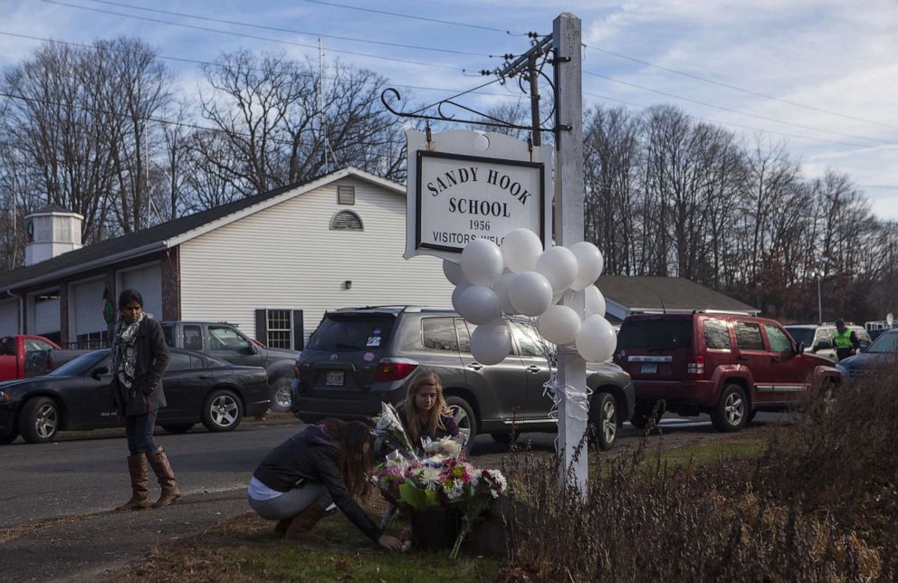 PHOTO: Local residents place flowers near the Sandy Hook Elementary School for the 28 children and faculty shot and killed one day earlier in Sandy Hook, Conn., Dec. 15, 2012.